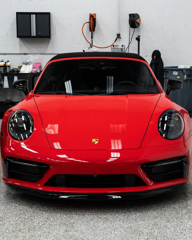 Front bumper and hood of a red Porsche receiving paint protection film coverage.